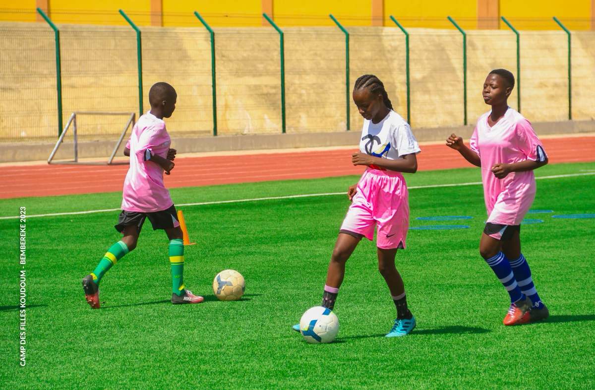 Trois joueuses en tenue rose travaillent la conduite de balle lors du camp des filles de Bembèrèkè.