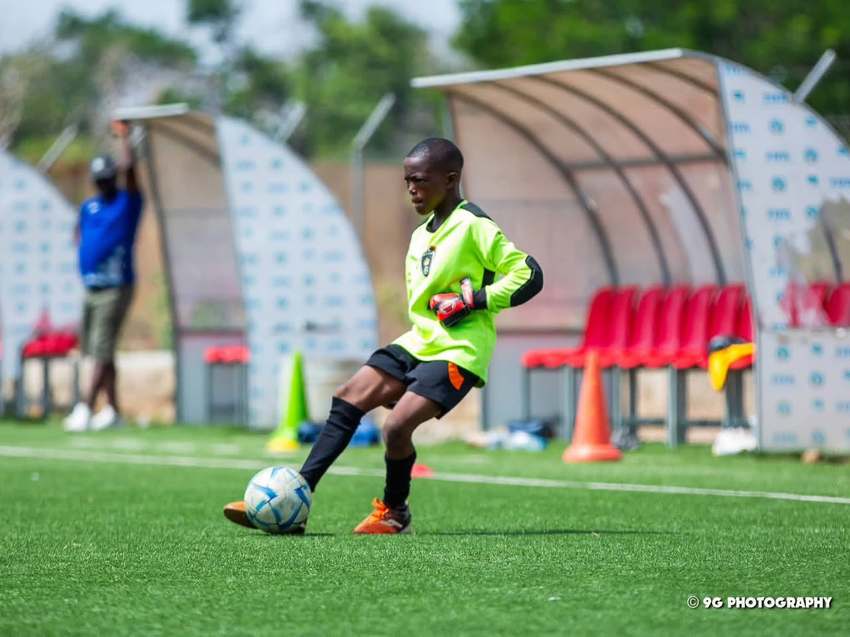 Un jeune gardien de but relance le ballon au pied.