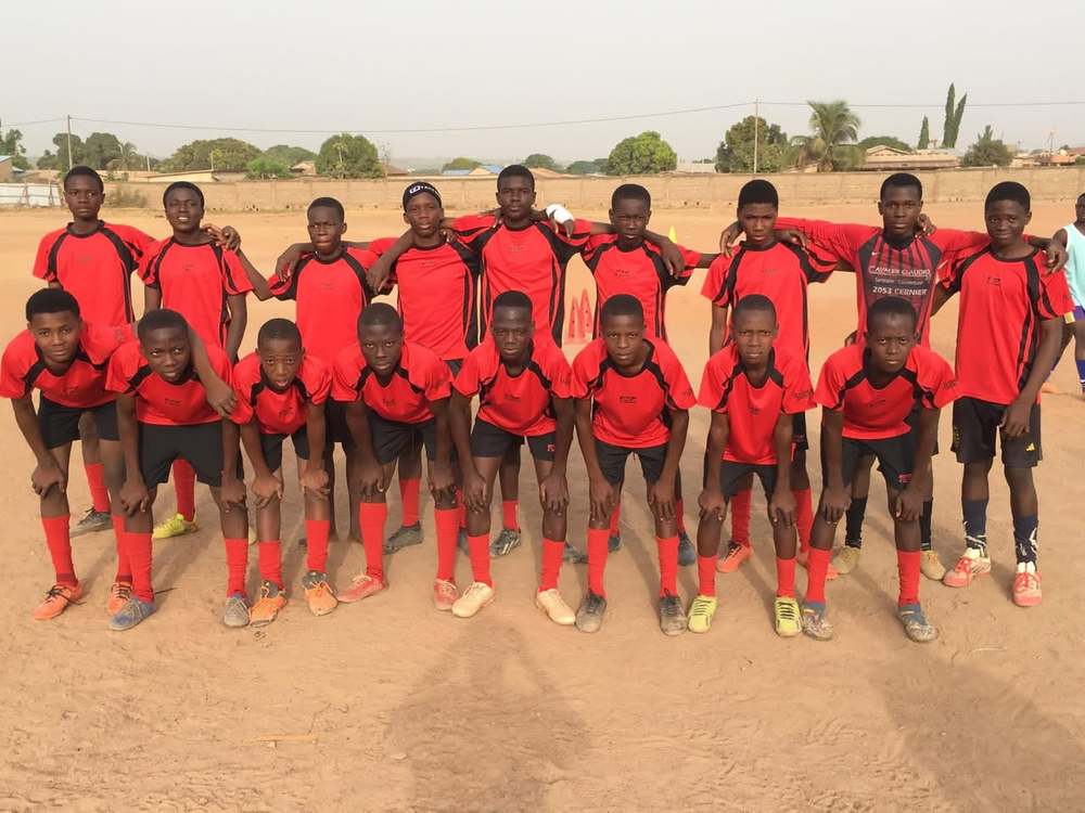 Une équipe de Hooli Académie en tenue rouge et noire, sur le terrain de sable.